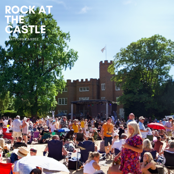 Image shows crowds of people in the sunshine listening to music